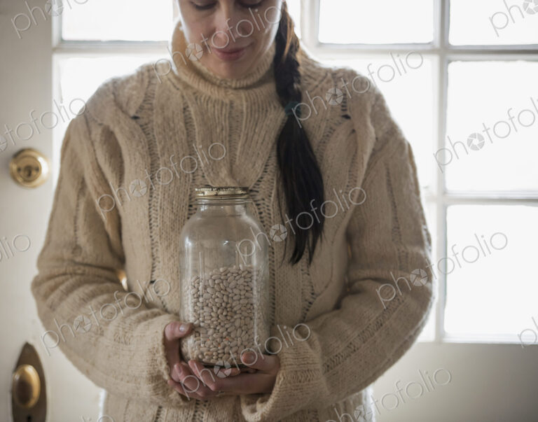 An organic farm in winter in New York State, USA. A woman in a cable knit sweater,…