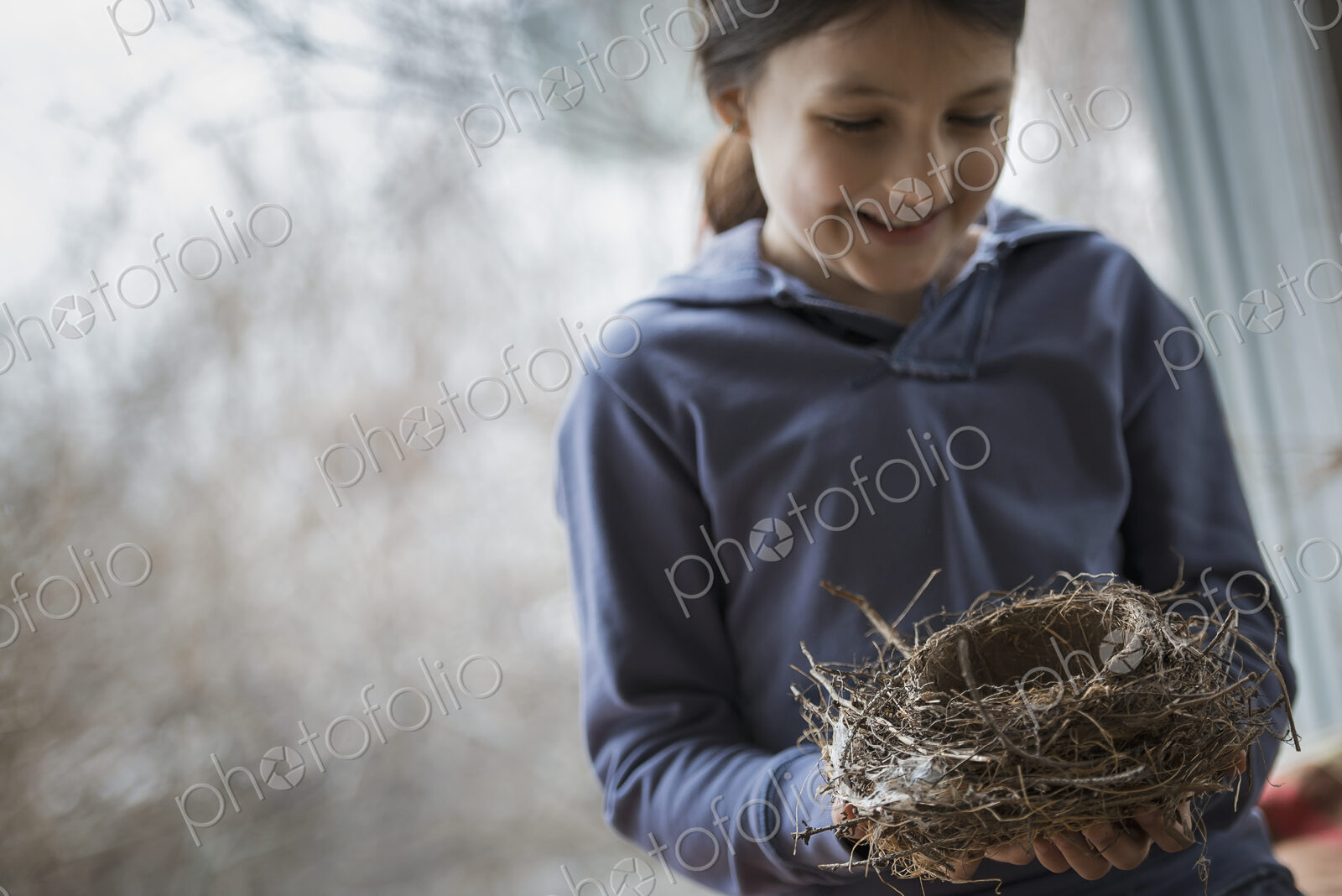 An organic farm in winter in New York State, USA. A young girl holding a bird’s nest…
