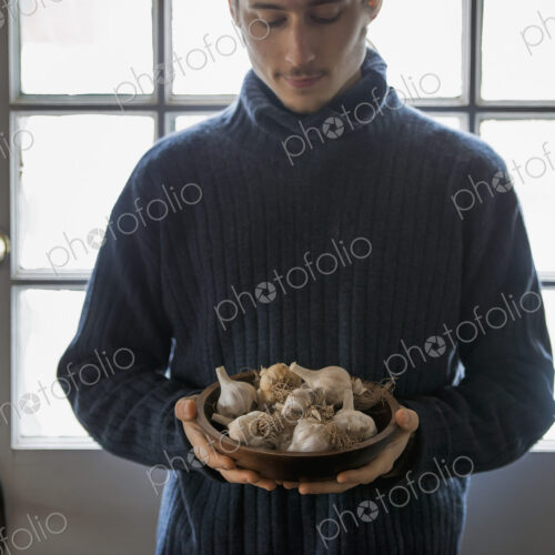 An organic farm in winter in New York State, USA. A young man holding a bow of garlic…