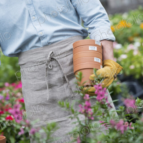 An organic flower plant nursery. A man carrying plant pots. An organic flower plant nursery. A man carrying plant pots.