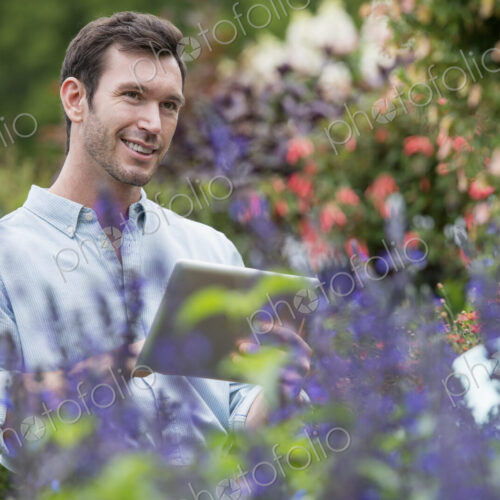 An organic flower plant nursery. A man working, using a digital tablet. An organic flower plant nursery. A man working, using a digital tablet.