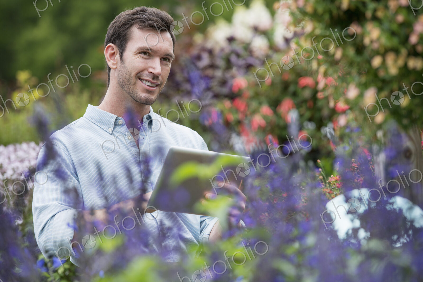 An organic flower plant nursery. A man working, using a digital tablet.