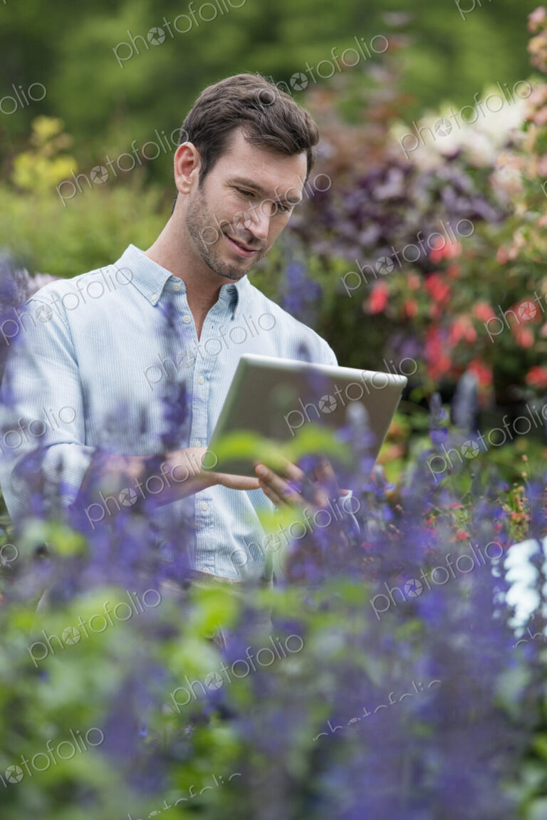 An organic flower plant nursery. A man working, using a digital tablet.