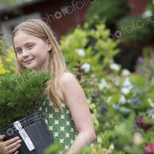 An organic flower plant nursery. A young girl carrying a plant in a pot. An organic flower plant nursery. A young girl carrying a plant in a pot.