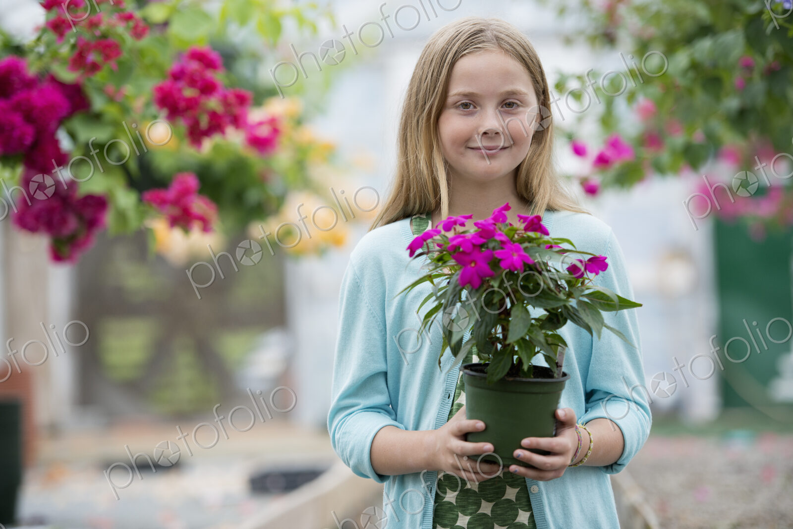 An organic flower plant nursery. A young girl holding a flowering plant.