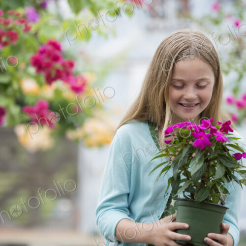 An organic flower plant nursery. A young girl holding a flowering plant. An organic flower plant nursery. A young girl holding a flowering plant.