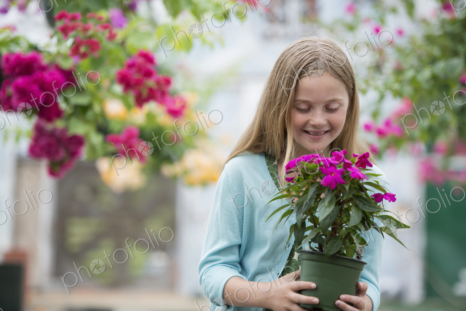 An organic flower plant nursery. A young girl holding a flowering plant.