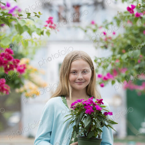 An organic flower plant nursery. A young girl holding a flowering plant. An organic flower plant nursery. A young girl holding a flowering plant.