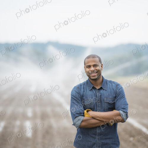 An organic vegetable farm, with water sprinklers irrigating the fields. A man in… An organic vegetable farm, with water sprinklers irrigating the fields. A man in…
