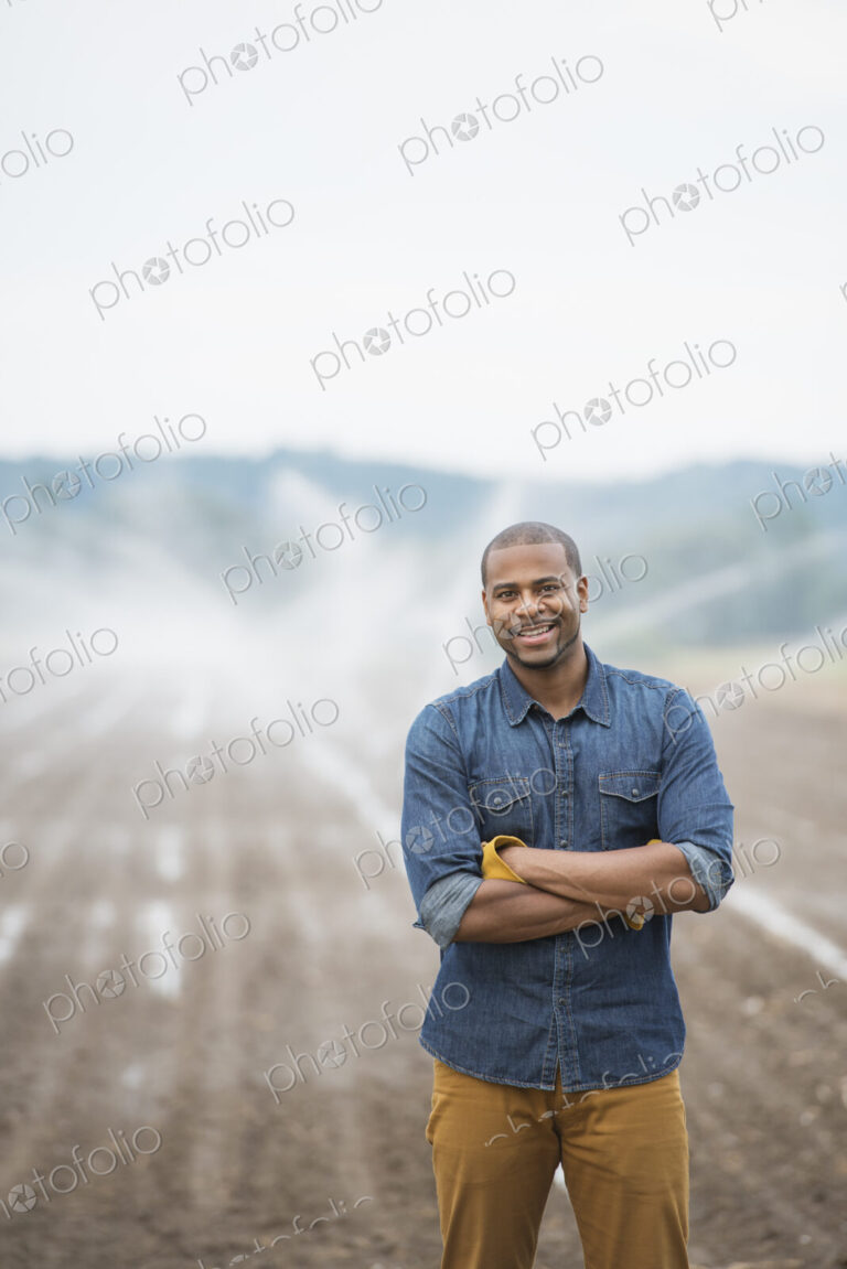 An organic vegetable farm, with water sprinklers irrigating the fields. A man in…