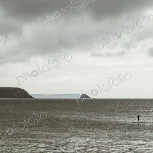 An overcast day with clouds, a view across a calm sea, to distant headlands and an… An overcast day with clouds, a view across a calm sea, to distant headlands and an…