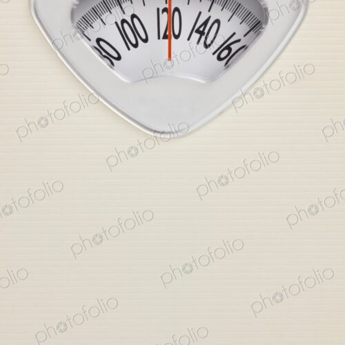 Analog bathroom scale close-up with red needle pointing at 120 pounds. Health and…
