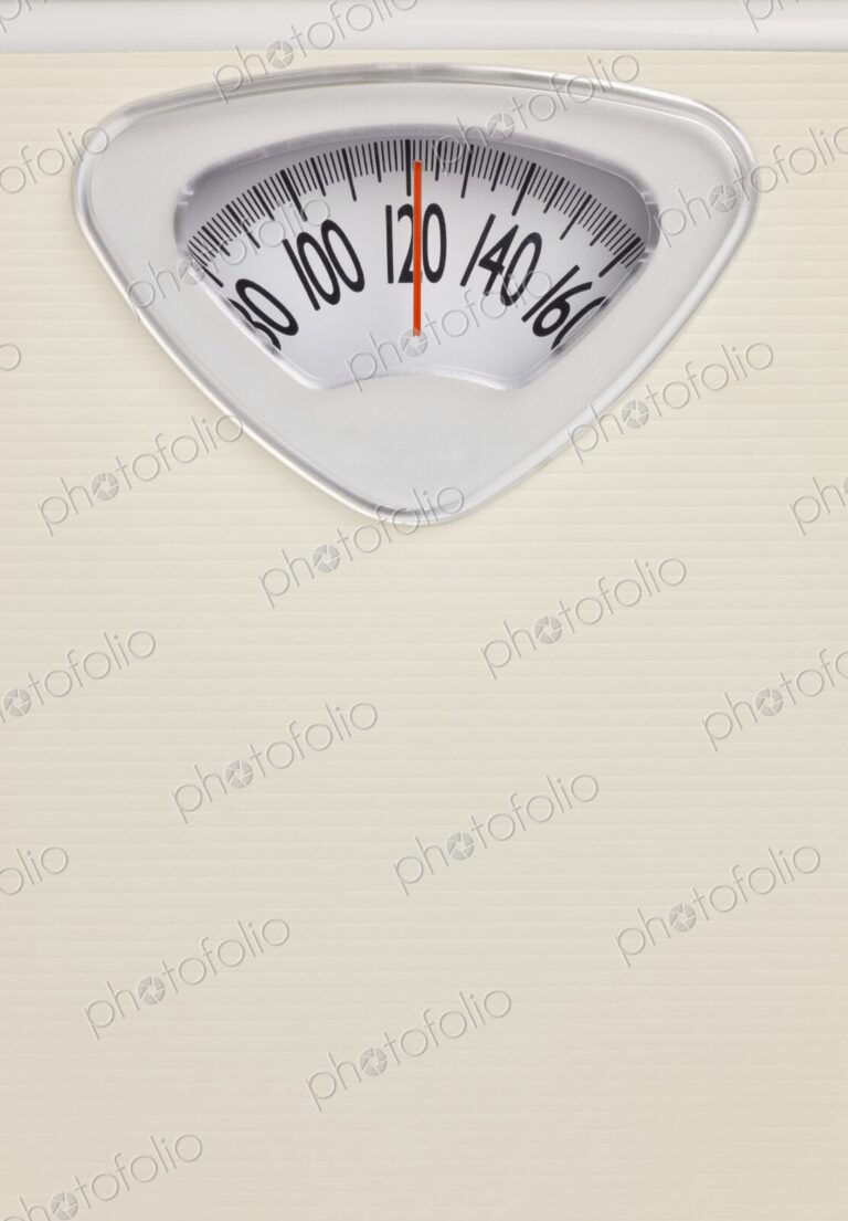 Analog bathroom scale close-up with red needle pointing at 120 pounds. Health and…