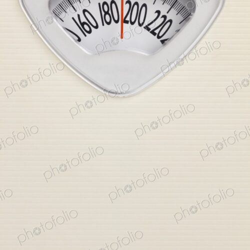 Analog bathroom scale close-up with red needle pointing near 200 pounds. Health and…