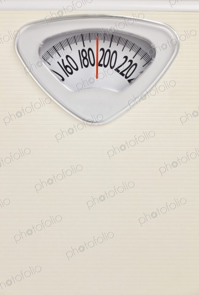 Analog bathroom scale close-up with red needle pointing near 200 pounds. Health and…