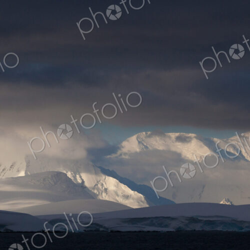 Antarctica. Snow covered peaks with low cloud. Antarctica. Snow covered peaks with low cloud.