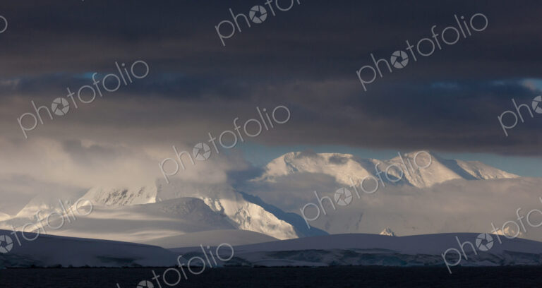 Antarctica. Snow covered peaks with low cloud.