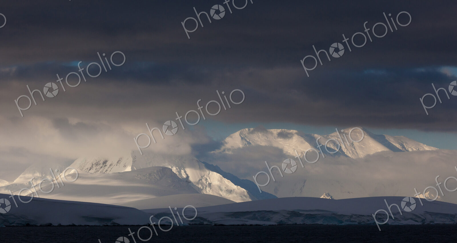 Antarctica. Snow covered peaks with low cloud.