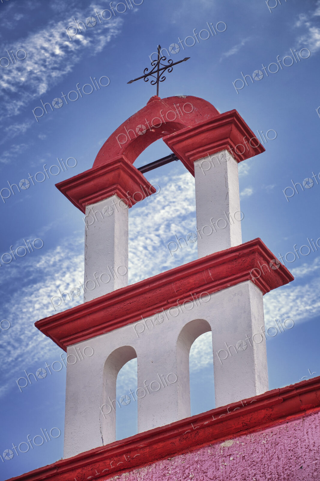 Architectural detail, red and white paint and iron cross on a church rooftop in Cancun.