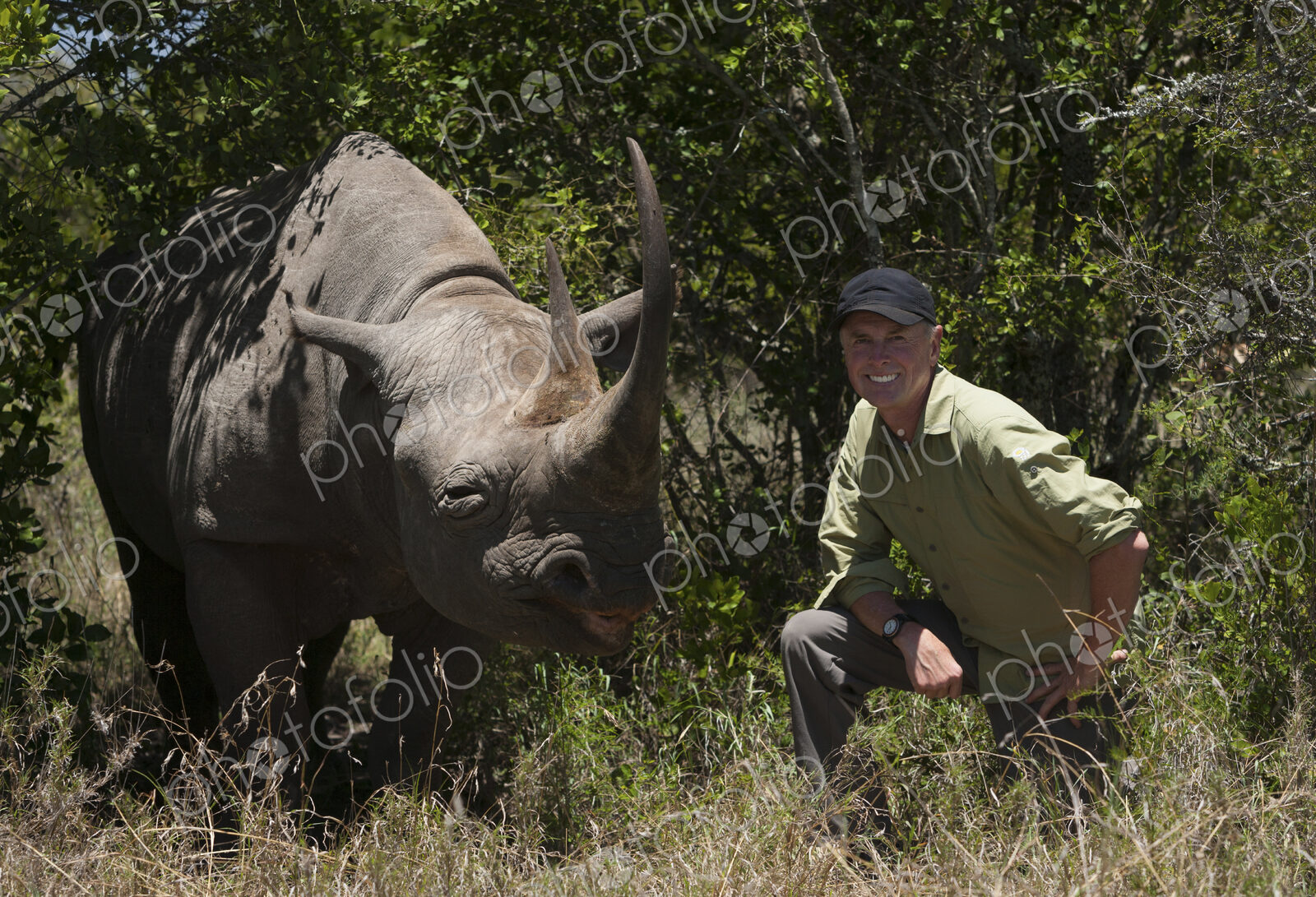 Art Wolfe, photographer kneeling next to a white rhinoceros in Kenya.