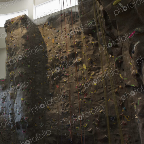Artificial climbing wall with ropes in indoor climbing centre.