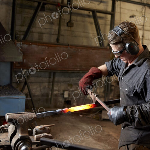 Artisan metal worker shaping a red hot piece of metal Artisan metal worker shaping a red hot piece of metal