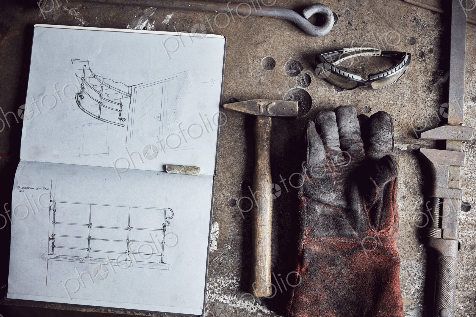 Artisan metalworker’s tools, sketches in a notebook and a glove