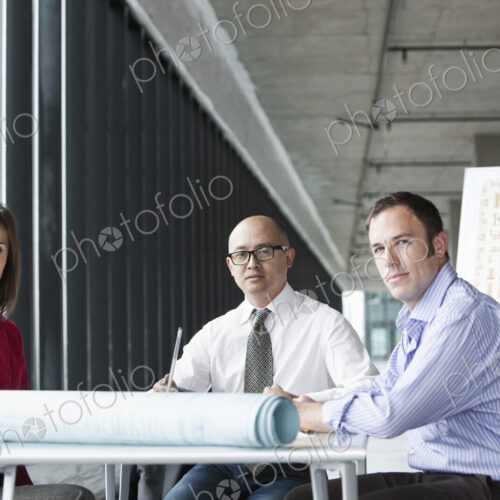 Asian architect with caucasian man and woman managers in a new raw business space.