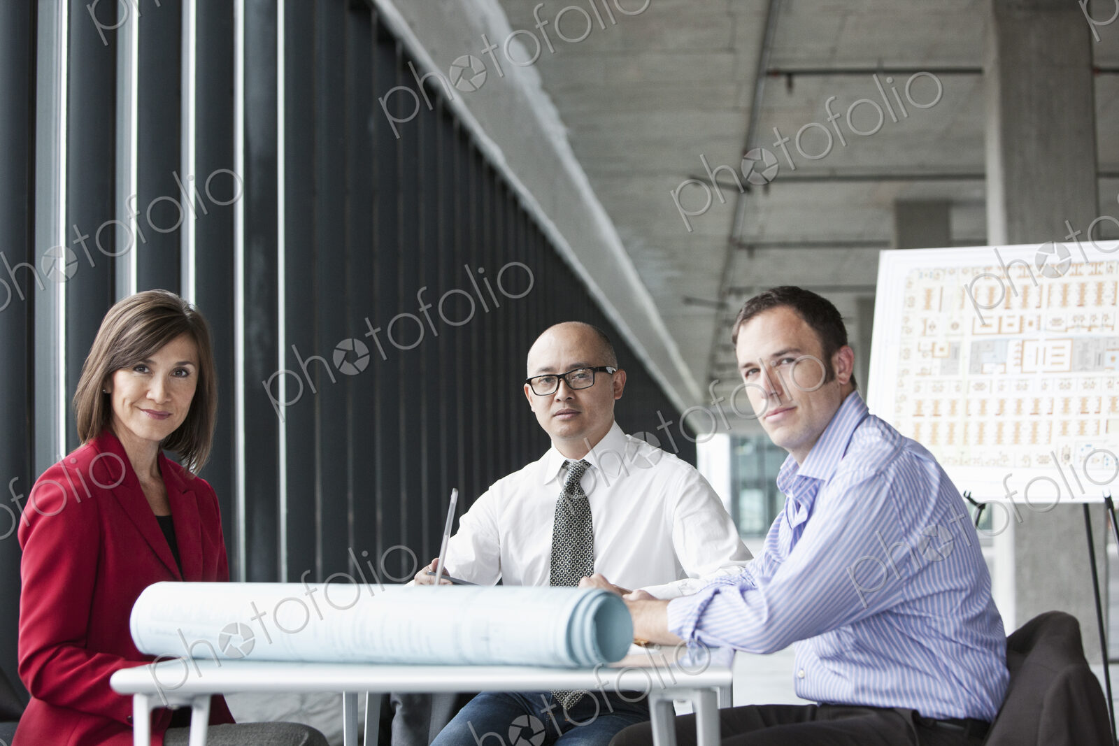 Asian architect with caucasian man and woman managers in a new raw business space.