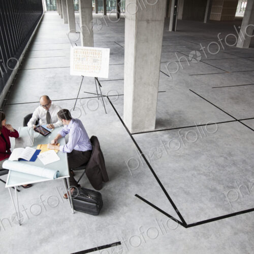 Asian architect with caucasian man and woman planning workspace in a new raw office…