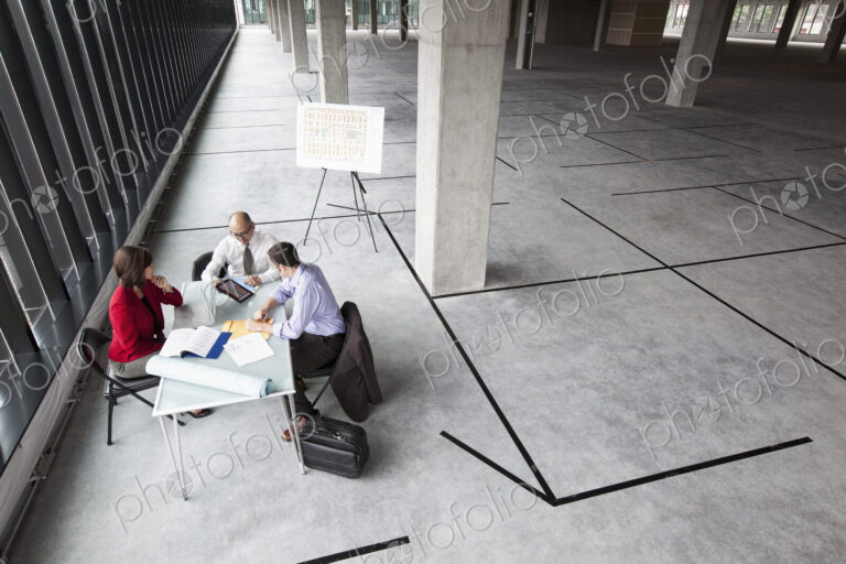Asian architect with caucasian man and woman planning workspace in a new raw office…