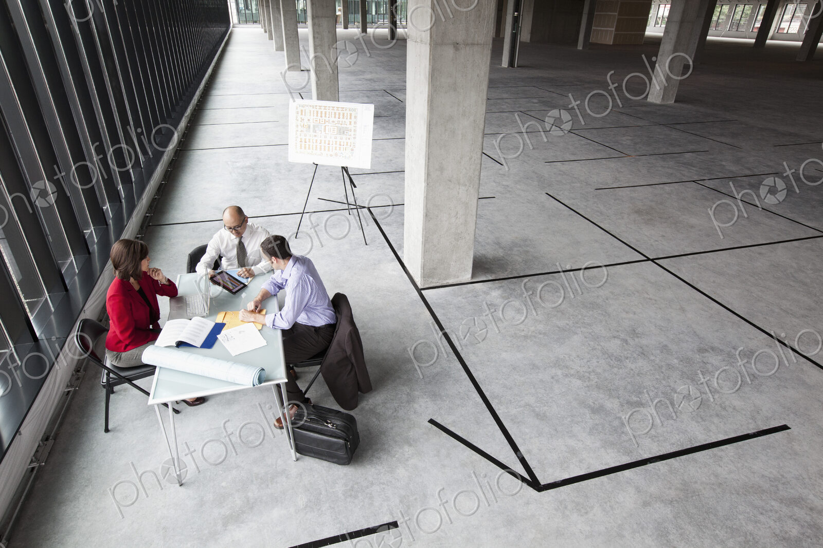 Asian architect with caucasian man and woman planning workspace in a new raw office…
