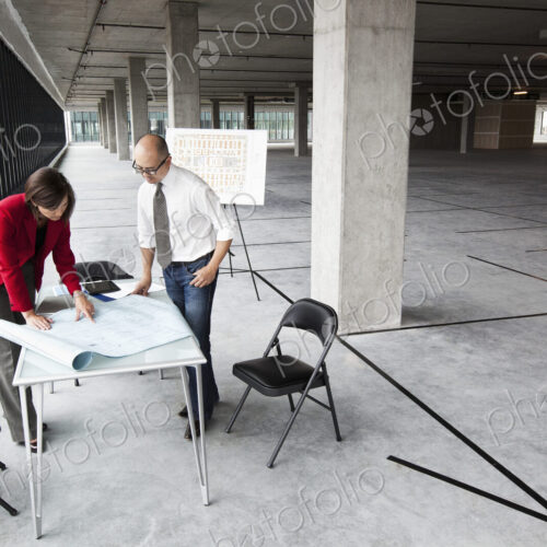 Asian architect with caucasian woman planning workspaces in a new raw office location