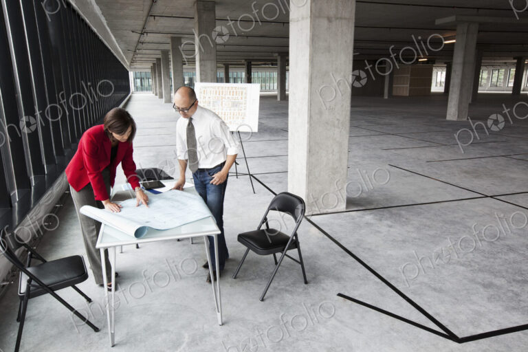 Asian architect with caucasian woman planning workspaces in a new raw office location