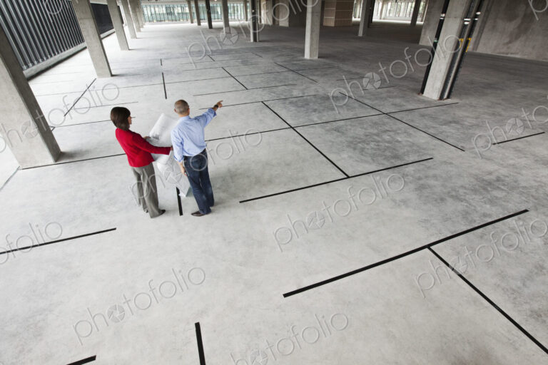 Asian architect with caucasian woman planning workspaces in a new raw office location