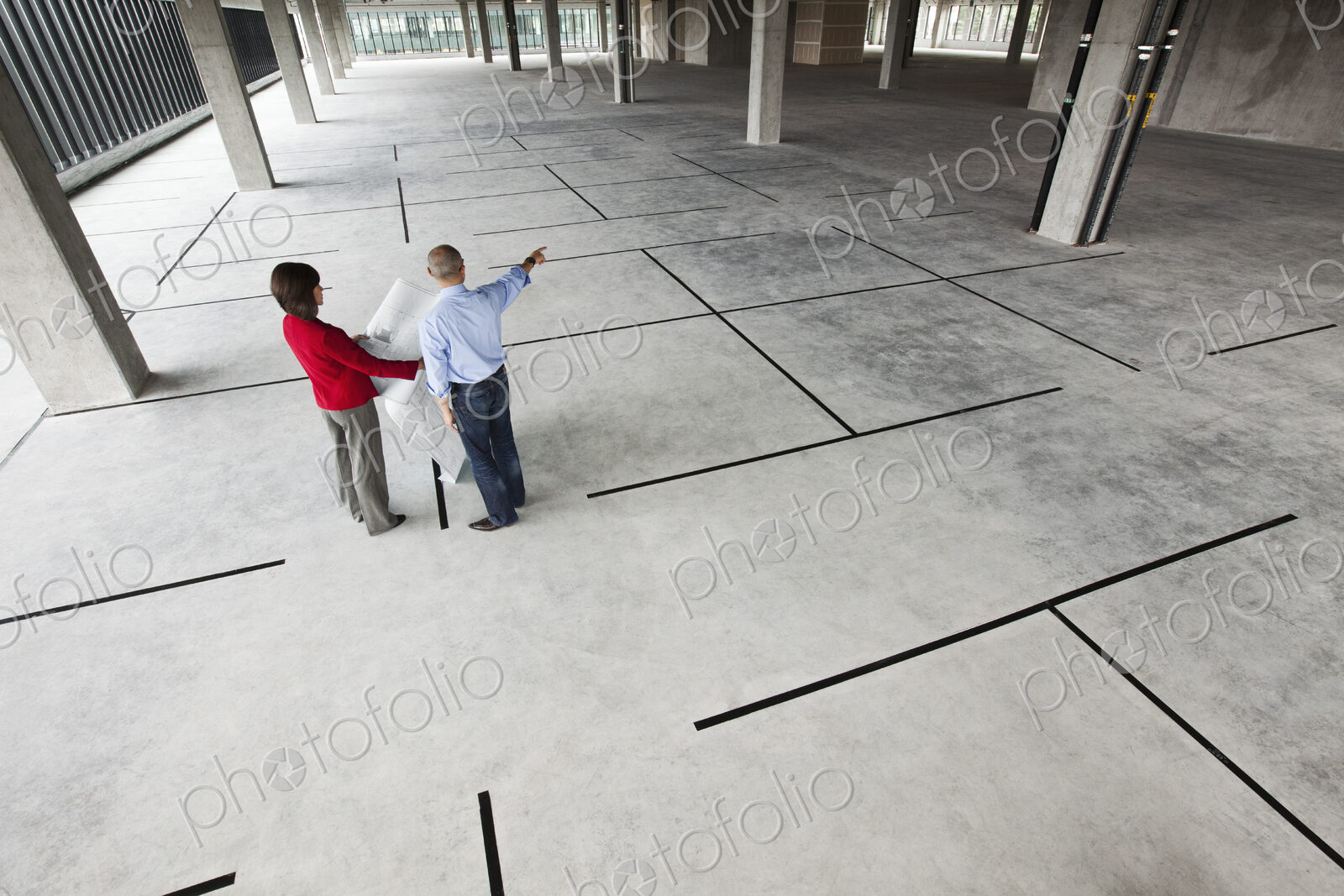 Asian architect with caucasian woman planning workspaces in a new raw office location