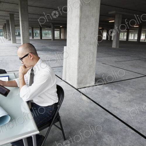 Asian architect woking on workspaces in a new raw office location.