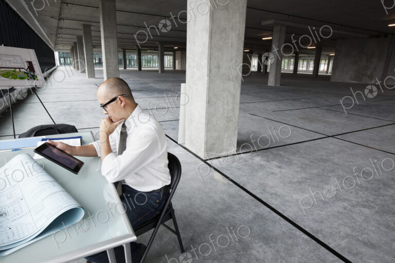 Asian architect woking on workspaces in a new raw office location.