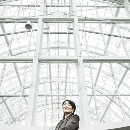 Asian business woman in a suit coat standing in a glass covered walkway Asian business woman in a suit coat standing in a glass covered walkway