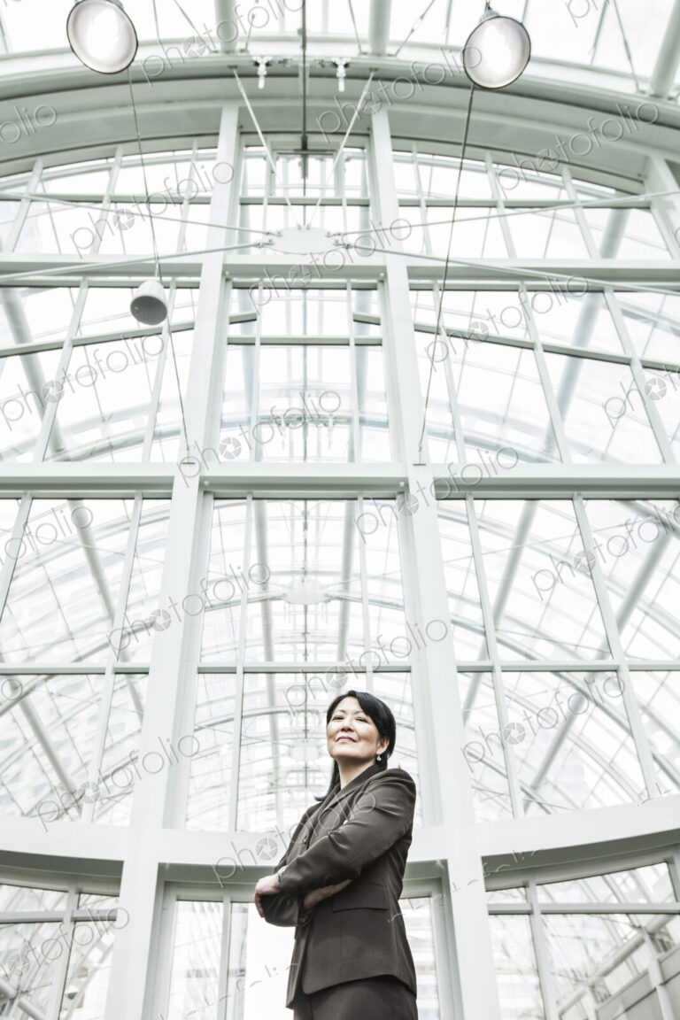 Asian business woman in a suit coat standing in a glass covered walkway