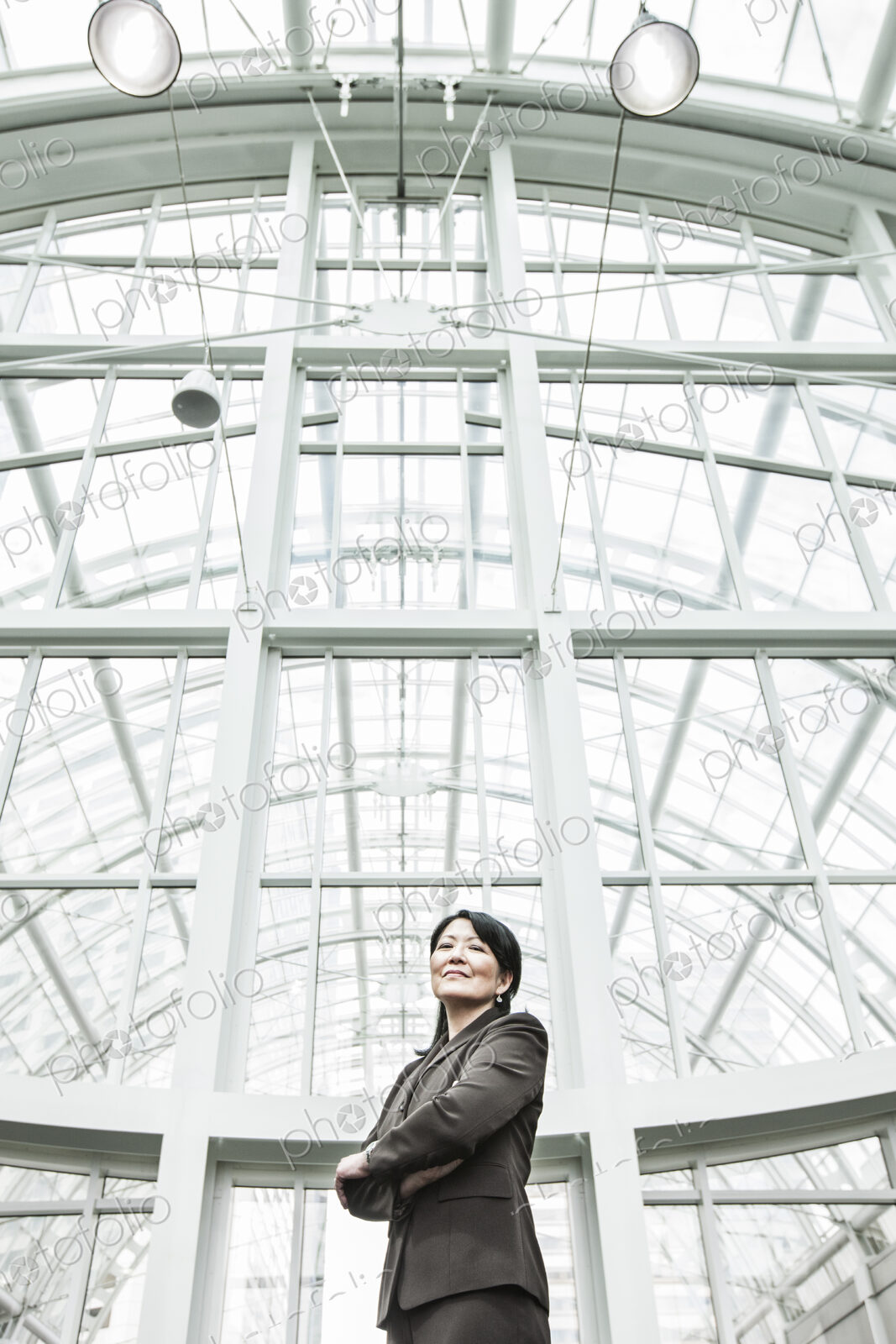 Asian business woman in a suit coat standing in a glass covered walkway