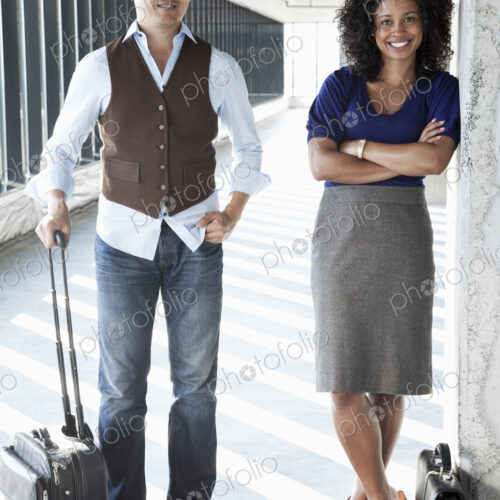 Asian businessman and black businesswoman in a large empty office space lit by the…
