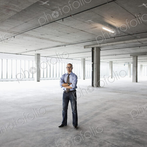 Asian businessman in a new empty raw office space.