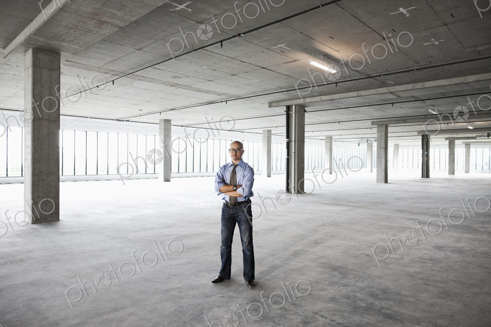 Asian businessman in a new empty raw office space.