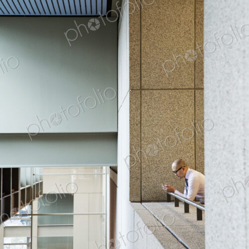 Asian businessman standing in a convention center hallway working on a notebook computer. Asian businessman standing in a convention center hallway working on a notebook computer.