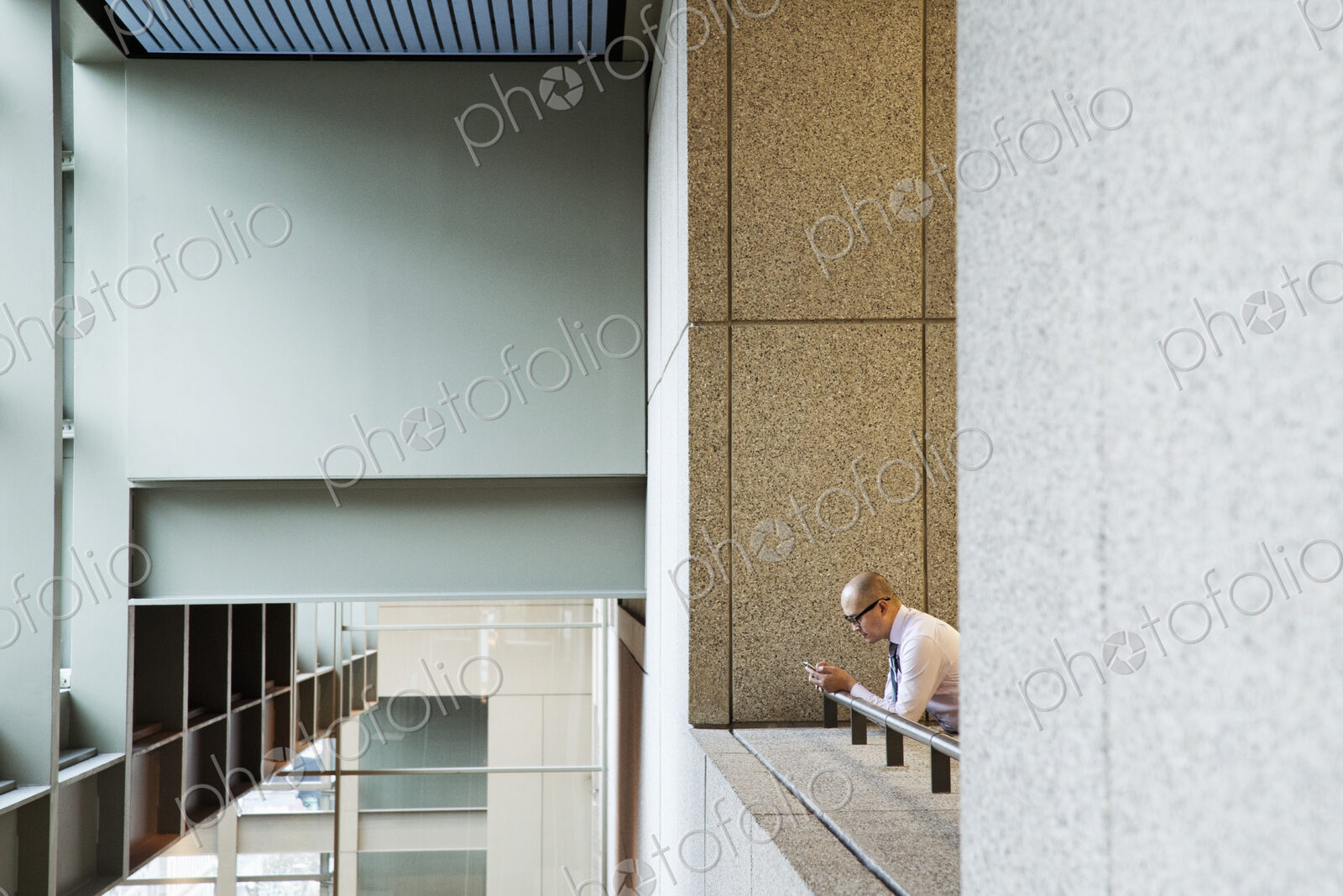 Asian businessman standing in a convention center hallway working on a notebook computer.