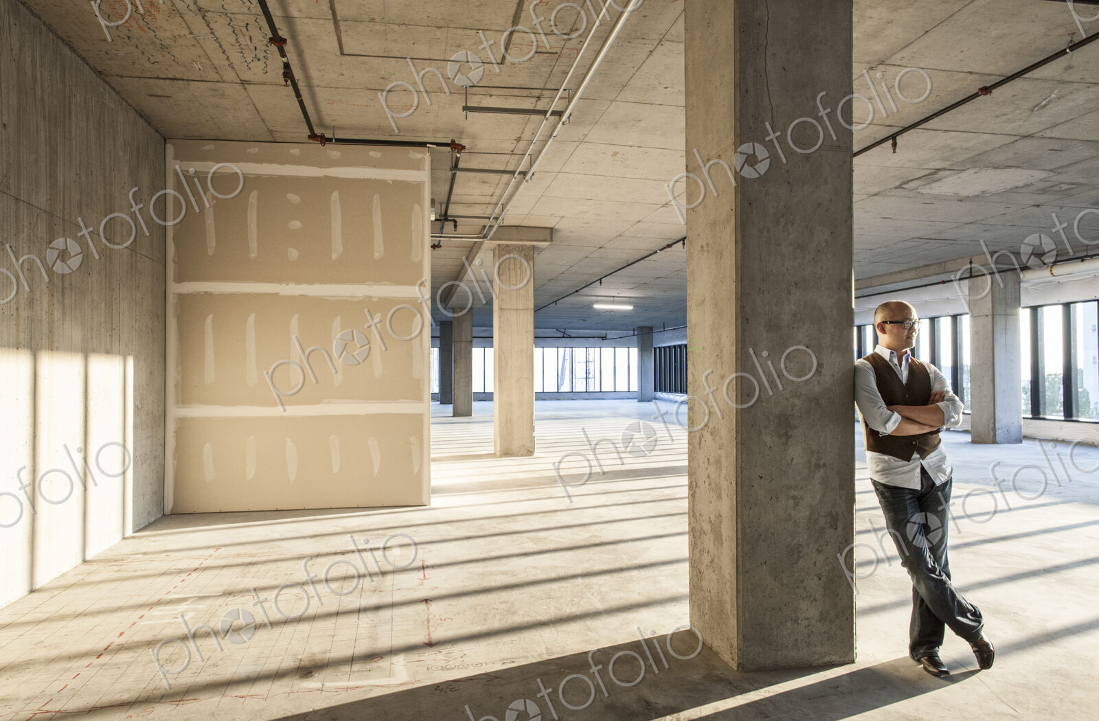 Asian businessman standing in a large empty raw office space.