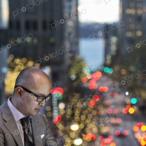 Asian businessman working on his phone by a window with city view Asian businessman working on his phone by a window with city view