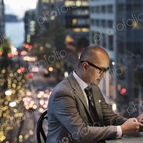 Asian businessman working on his phone by a window with city view Asian businessman working on his phone by a window with city view