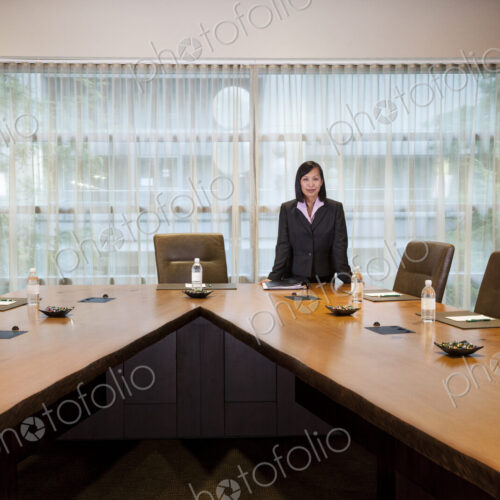 Asian businesswoman at the head of a conference room table.